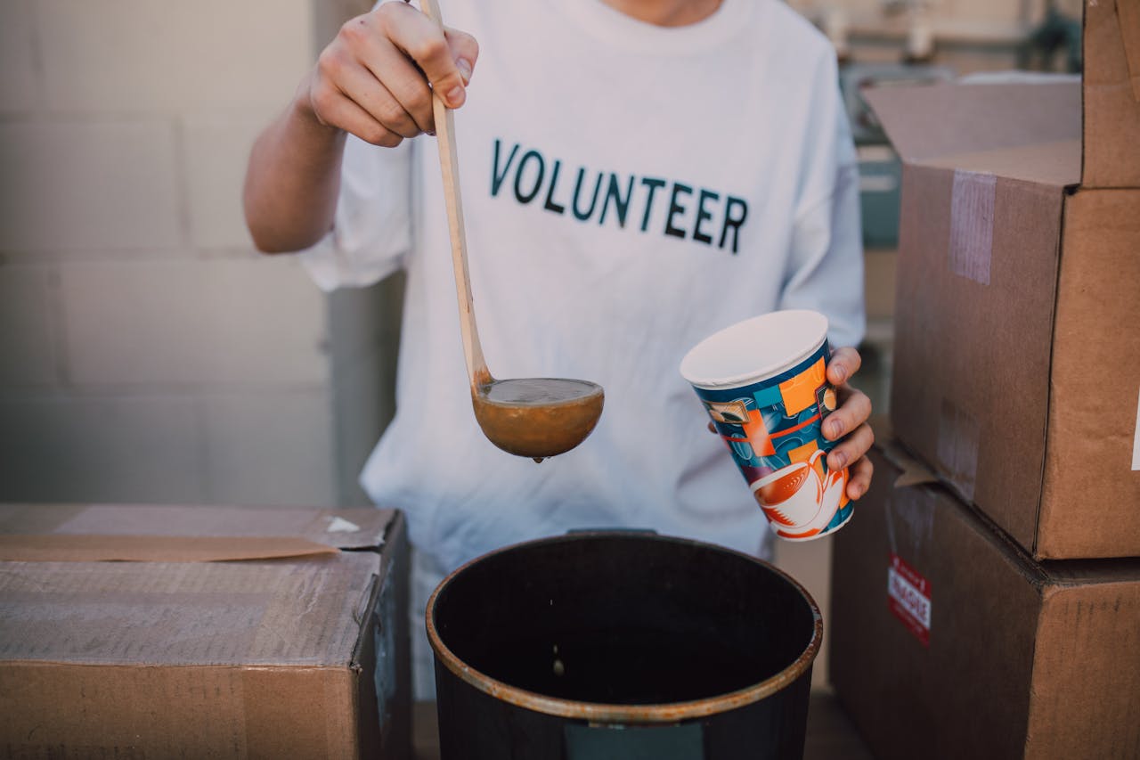 A volunteer in a t-shirt serving soup at a community event. Helping hand.