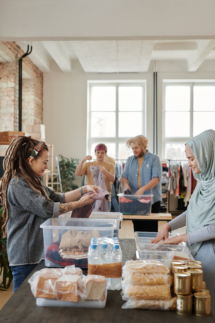 creative-01 A diverse group of volunteers sorting clothes and food items at an indoor donation center.