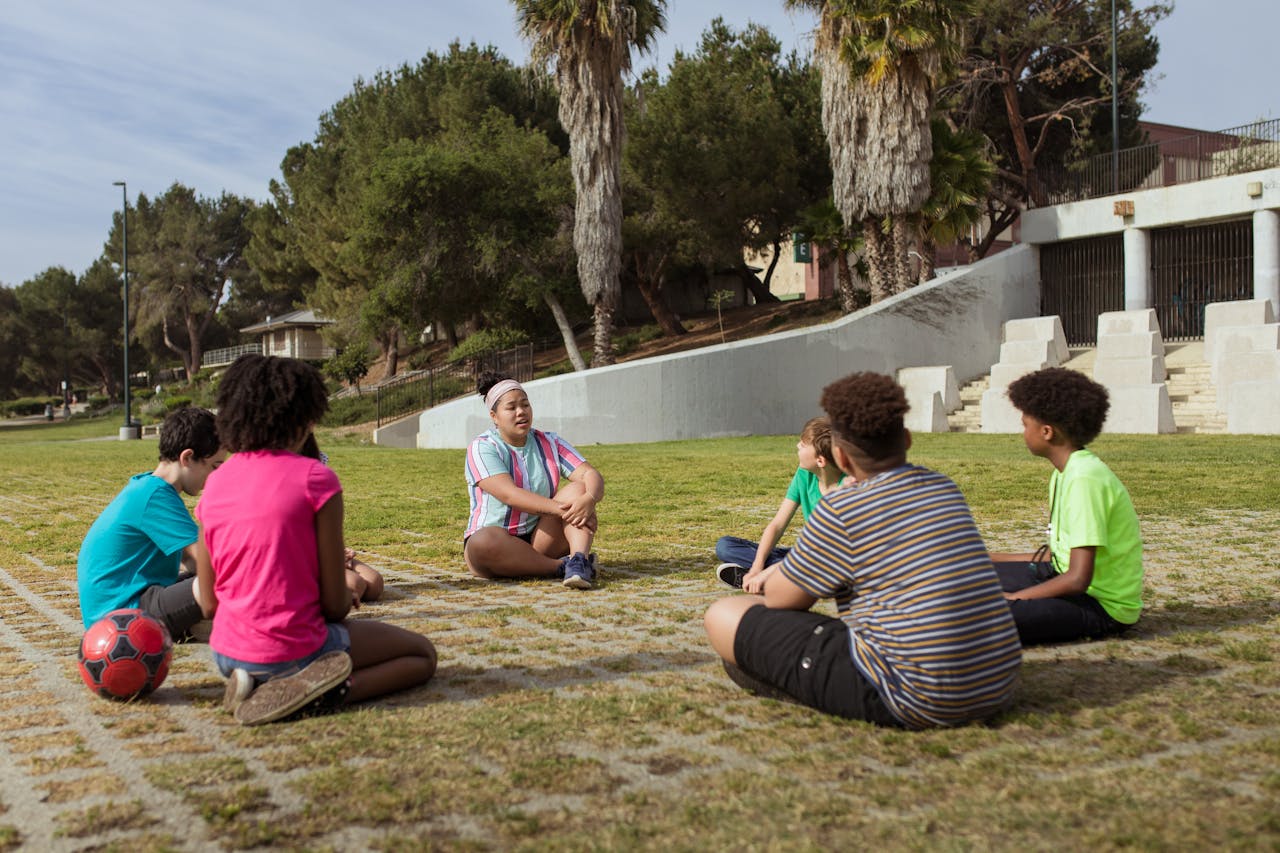 brand-03 Group of kids discussing and learning outdoors in a park setting.